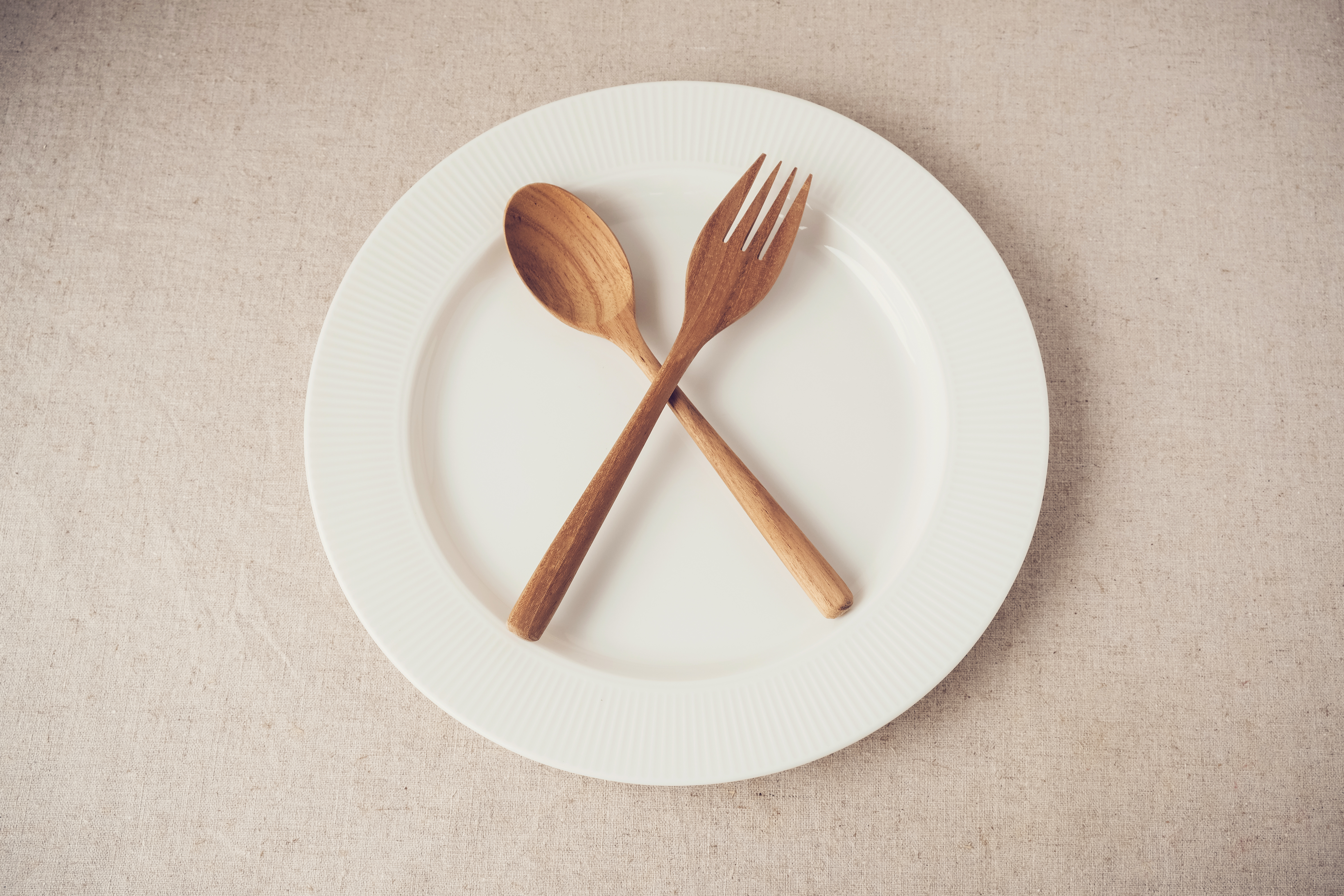 A white plate with two wooden spoons and fork on it.