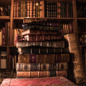 A pile of books in front of a bookshelf.