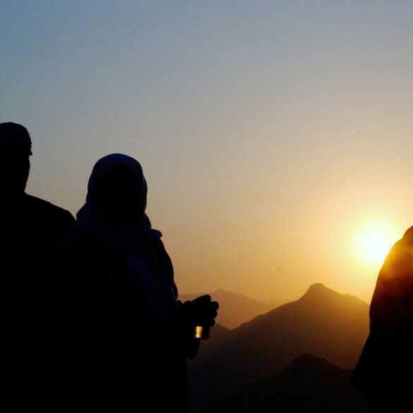 A couple of people standing in front of the sun.