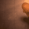 A man standing on the floor in front of a wall.
