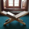 A book is sitting on the ground in front of an open window.