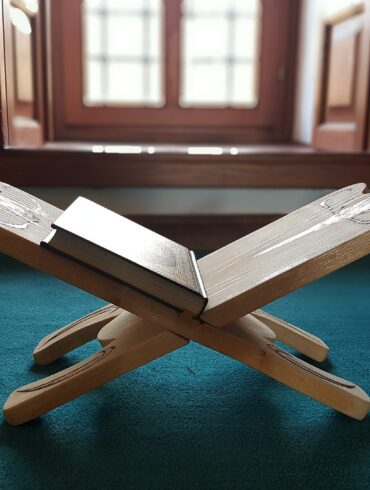 A book is sitting on the ground in front of an open window.