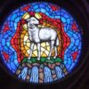 A stained glass window with a sheep in the center.