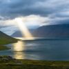 A lake with sun rays coming through the clouds.