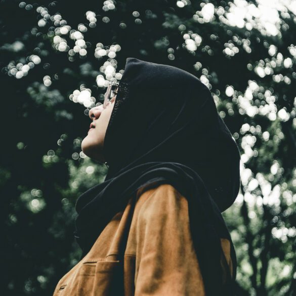 A person wearing a hood and jacket in the woods.