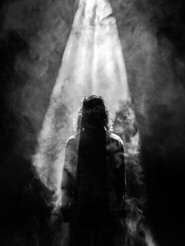 A person standing in the light of an open window.