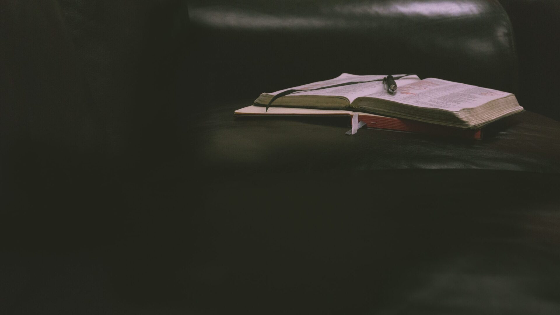 A book is open on the table in front of a window.