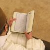 A person holding an open book in their hands.