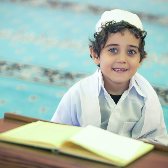 A young boy sitting at a table with an open book.