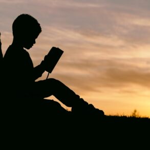 A person sitting on the ground reading a book.