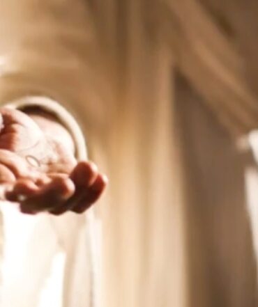 A person holding onto the curtain of their bedroom.